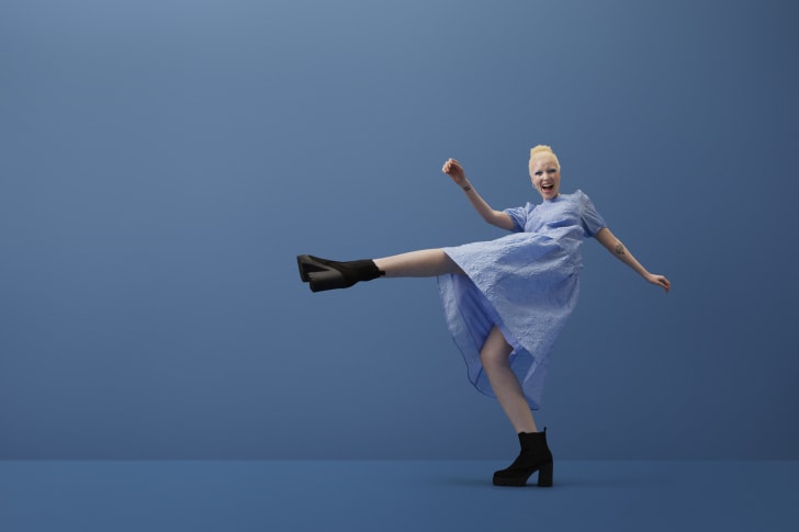 Woman kicking on blue background